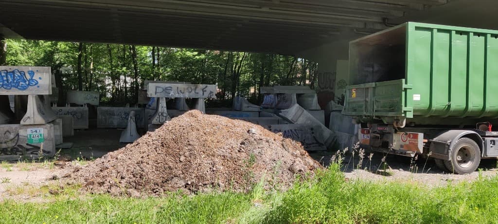 Houtsnippers en mulch tussen betonblokken onder de brug