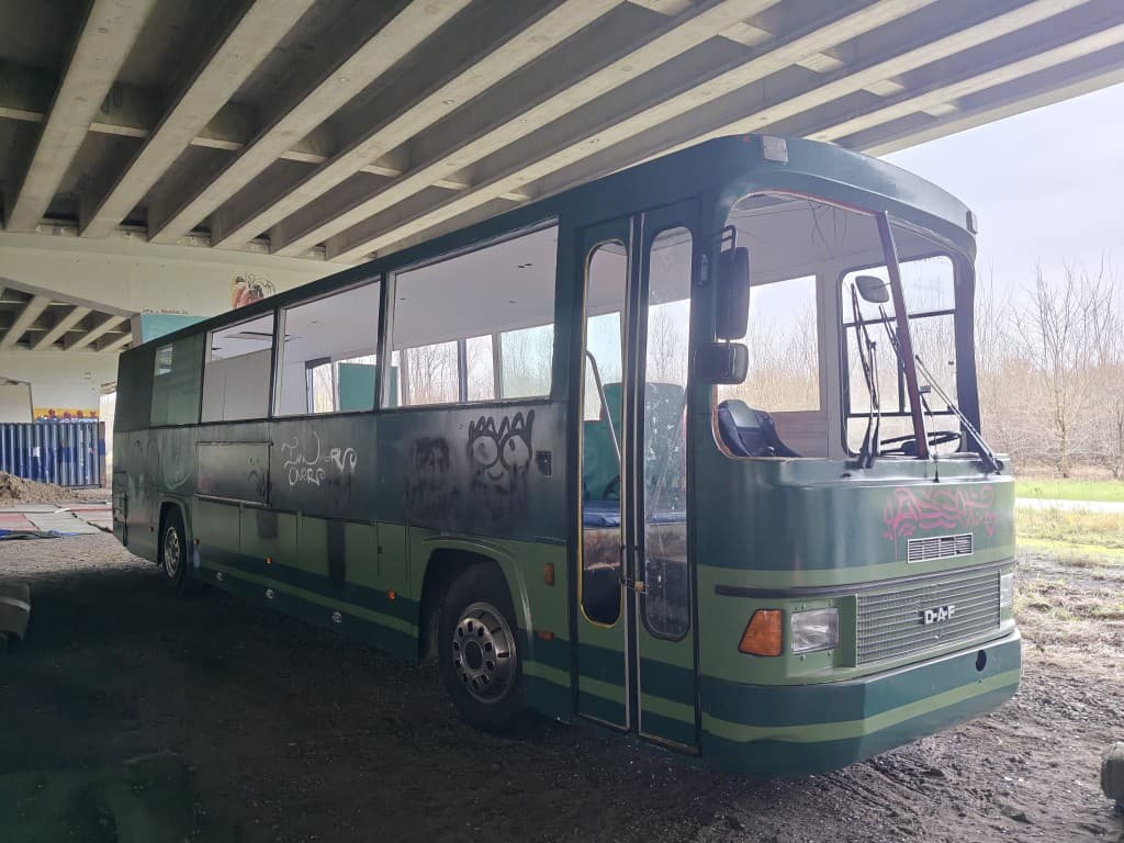 Groene DAF-bus onder het viaduct